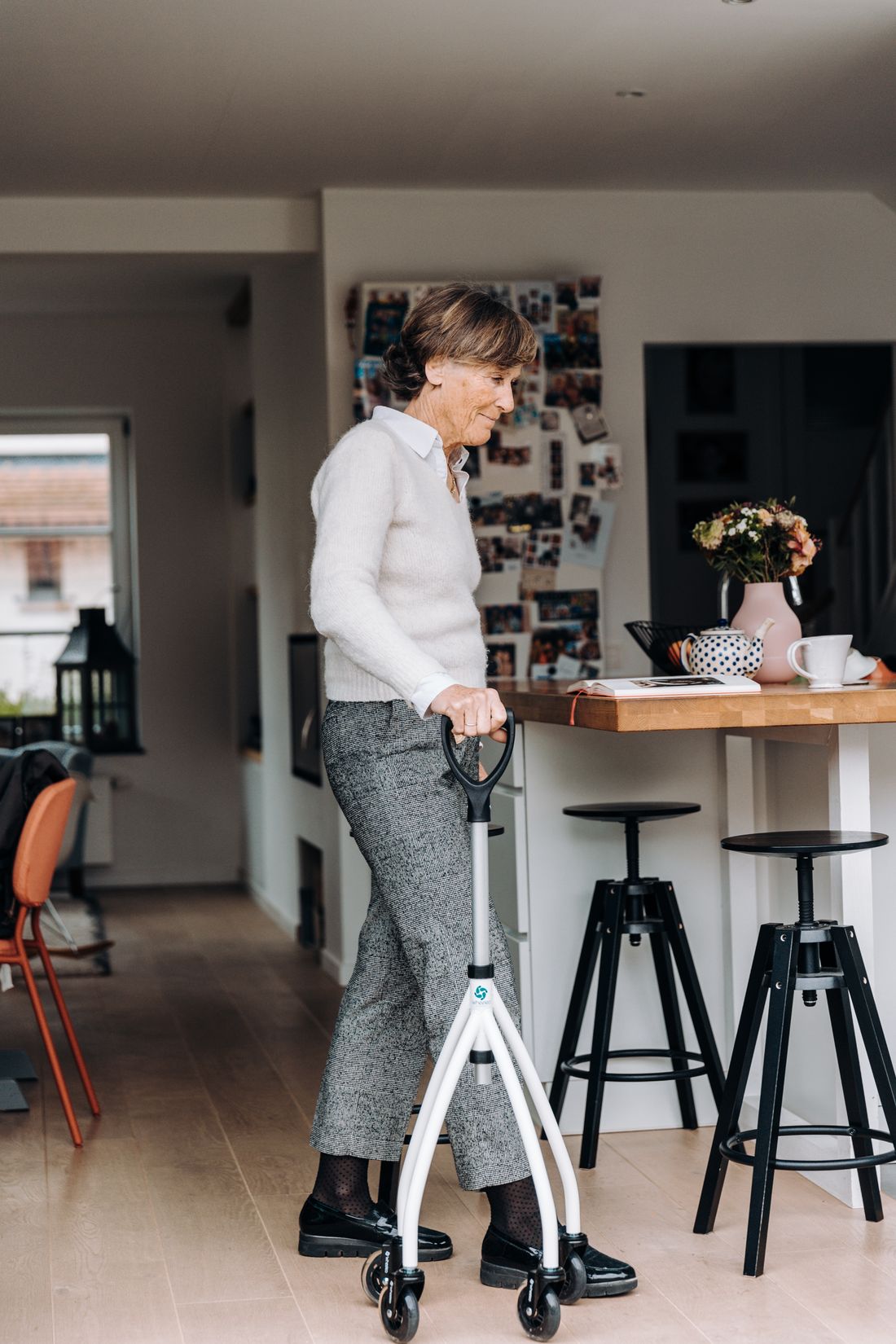 Older woman using walker in home kitchen. Illustrative stock photograph