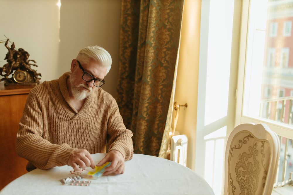 Older man sorting pills into an organizer. Illustrative stock photograph